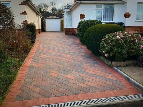 Brindle herringbone block paving driveway with a red edge and channel drain across the front