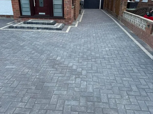 Grey herringbone block paving driveway running past new front steps with a light border