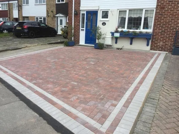 Red block paving driveway with a double silver-grey border in front of a semi-detached house